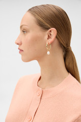 Profile view of model wearing the Oroton Ali Large Charm Huggies in Gold and Premium brass material for Women .