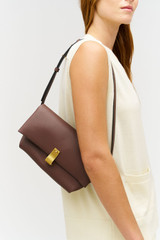 Profile view of model wearing the Oroton Etta Medium Clutch in Bear Brown and Premium smooth leather for Women .