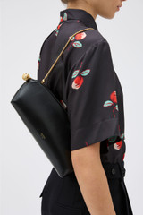 Profile view of model wearing the Oroton Naia Clutch in Black and Premium crackle leather for Women .