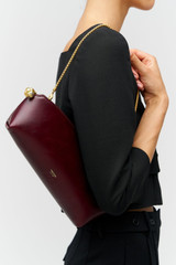 Profile view of model wearing the Oroton Naia Clutch in CURRANT and Premium crackle leather for Women .