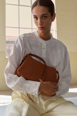 Profile view of model wearing the Oroton Cali Shoulder Bag in Amber and Premium smooth leather for Women .