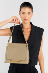 Profile view of model wearing the Oroton Elm Medium Satchel in Mushroom and Premium smooth pebble leather for Women .