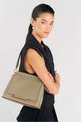 Profile view of model wearing the Oroton Elm Medium Satchel in Mushroom and Premium smooth pebble leather for Women .
