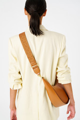 Profile view of model wearing the Oroton Logo Webbing Bag Strap in Amber and Smooth leather for Women .