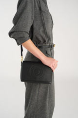 Profile view of model wearing the Oroton Polly Flap Over Crossbody in Black and Premium pebble leather for Women .
