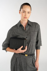 Profile view of model wearing the Oroton Polly Flap Over Crossbody in Black and Premium pebble leather for Women .