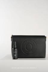 Profile view of model wearing the Oroton Polly Flap Over Crossbody in Black and Premium pebble leather for Women .