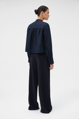 Profile view of model wearing the Oroton Flat Front Pant in North Sea and 100% wool fabric for Women .