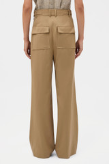 Profile view of model wearing the  PLEAT PANT in Hazelnut and 97% wool and 3% spandex blend fabric for Women