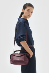 Profile view of model wearing the Oroton Mica Bowler in CURRANT and Premium pebble grain leather for Women .
