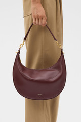Profile view of model wearing the Oroton Florence Medium Hobo in Currant and Smooth leather material for Women .