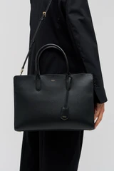 Profile view of model wearing the Oroton Muse 15" Worker Tote in Black and Saffiano leather exterior for Women .