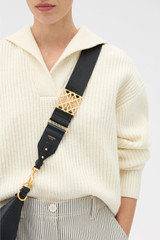 Profile view of model wearing the Oroton Lane Bag Strap in Black and Premium webbing material for Women .