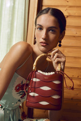 Profile view of model wearing the Oroton Leigh Ric Rac Bucket Bag in Cherry and Premium smooth leather for Women .
