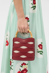 Profile view of model wearing the Oroton Leigh Ric Rac Bucket Bag in Cherry and Premium smooth leather for Women .