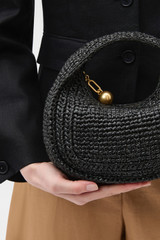 Profile view of model wearing the Oroton Clara Straw Mini Bag in Black and Woven straw material for Women . IP:4