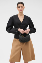 Profile view of model wearing the Oroton Clara Straw Mini Bag in Black and Woven straw material for Women .