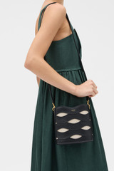 Profile view of model wearing the Oroton Leigh Ric Rac Bucket Bag in Black and Premium smooth leather for Women .