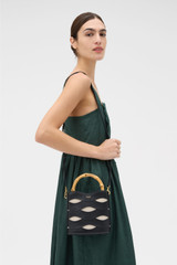 Profile view of model wearing the Oroton Leigh Ric Rac Bucket Bag in Black and Premium smooth leather for Women .