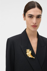 Profile view of model wearing the Oroton OAK BROOCH in Worn Gold and Premium brass material for Women .