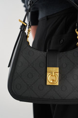 Profile view of model wearing the Oroton Yvonne Signature Baguette in Black and Nylon canvas base cloth material with PVC coating (70% PVC, 30% polyester) for Women .