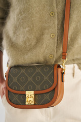 Profile view of model wearing the Oroton Yvonne Signature Small Saddle Bag in Cognac and Nylon canvas base cloth material with PVC coating (70% PVC, 30% polyester) for Women .