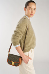 Profile view of model wearing the Oroton Yvonne Signature Small Saddle Bag in Cognac and Nylon canvas base cloth material with PVC coating (70% PVC, 30% polyester) for Women .