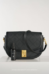 Profile view of model wearing the Oroton Yvonne Signature Small Saddle Bag in Black and Nylon canvas base cloth material with PVC coating (70% PVC, 30% polyester) for Women .