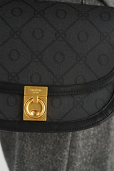 Profile view of model wearing the Oroton Yvonne Signature Medium Saddle Bag in Black and Nylon canvas base cloth material with PVC coating (70% PVC, 30% polyester) for Women .