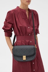 Profile view of model wearing the Oroton Yvonne Signature Medium Saddle Bag in Black and Nylon canvas base cloth material with PVC coating (70% PVC, 30% polyester) for Women .