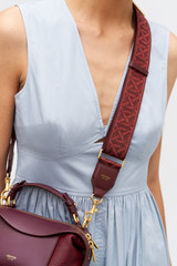 Profile view of model wearing the Oroton Logo Bag Strap in Currant and Premium leather and webbing material for Women .