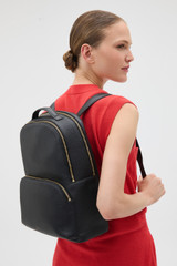 Profile view of model wearing the Oroton Dylan Large Zip Around Backpack in Black and Premium pebble leather for Women .
