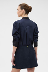 Profile view of model wearing the Oroton Button Detail Mini Skirt in NORTH SEA and 100% bonded salt-washed linen fabric for Women .