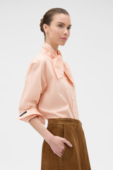 Profile view of model wearing the Oroton Tie Neck Shirt in APPLE PEACH and 100% cotton poplin fabric for Women . IP:3