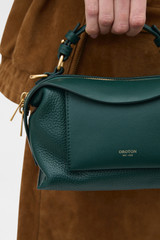 Profile view of model wearing the Oroton Mica Mini Bowler in IVY and Premium pebble leather for Women .