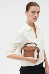 Profile view of model wearing the Oroton Mica Canvas Broguing Mini Bowler in Natural/Penny Brown and Premium canvas material for Women .