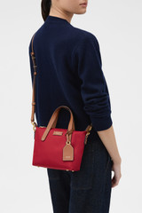 Profile view of model wearing the Oroton Lilly Nylon Small Crossbody Tote in DARK RUBY and Nylon fabric for Women .