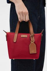 Profile view of model wearing the Oroton Lilly Nylon Small Crossbody Tote in DARK RUBY and Nylon fabric for Women .