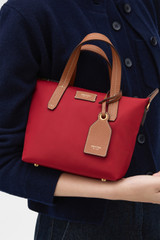 Profile view of model wearing the Oroton Lilly Nylon Small Crossbody Tote in DARK RUBY and Nylon fabric for Women .