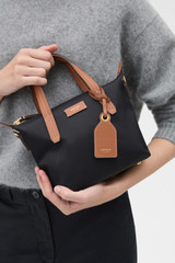 Profile view of model wearing the Oroton Lilly Nylon Small Crossbody Tote in Black/Cognac and Nylon fabric for Women .