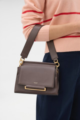 Profile view of model wearing the Oroton Elm Small Satchel in Coffee Bean and Premium smooth pebble leather for Women .