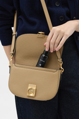 Profile view of model wearing the Oroton Yvonne Small Saddle Bag in MUSHROOM and Premium pebble leather for Women .