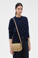 Profile view of model wearing the Oroton Yvonne Small Saddle Bag in MUSHROOM and Premium pebble leather for Women .