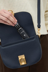 Profile view of model wearing the Oroton Yvonne Small Saddle Bag in DARK NAVY and Premium pebble leather for Women .