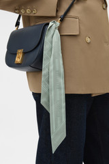 Profile view of model wearing the Oroton Eve Foulard Skinny Scarf in ROSEMARY and 100% polyester fabric for Women .