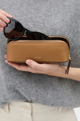 Profile view of model wearing the Oroton Lilly Duet Sunglasses Case in TAN and Premium pebble leather for Women .