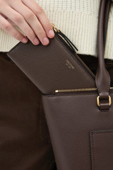 Profile view of model wearing the Oroton Eve Slim Zip Wallet in COFFEE BEAN and Premium pebble leather for Women .