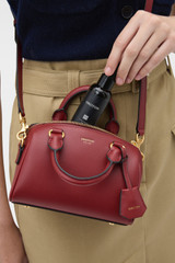 Profile view of model wearing the Oroton Harvey Tiny Barrel in BERRY and Premium smooth leather for Women .