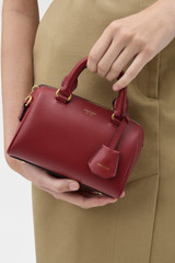 Profile view of model wearing the Oroton Harvey Tiny Barrel in BERRY and Premium smooth leather for Women .