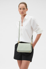 Profile view of model wearing the Oroton Eve Zip Top Crossbody in ROSEMARY and Premium pebble leather for Women .